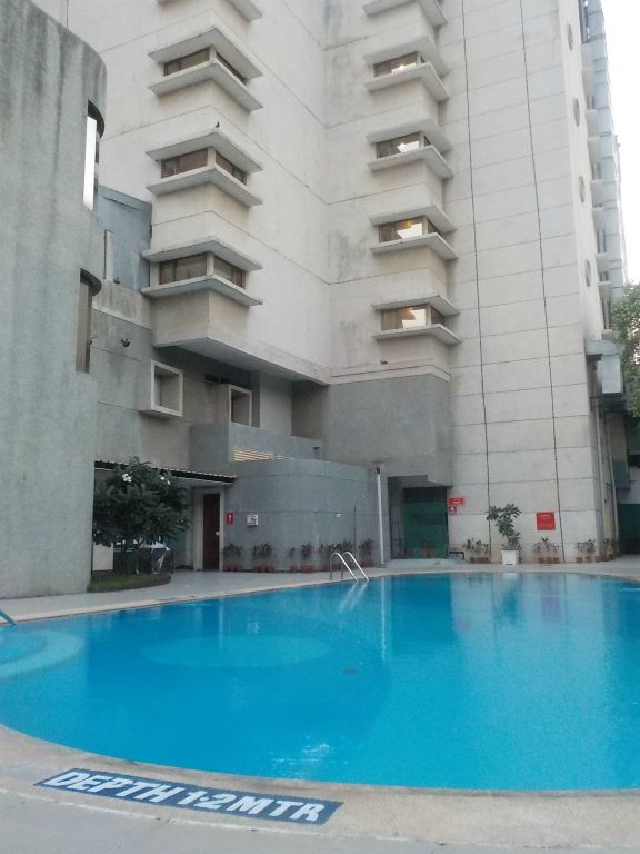 A swimming-pool behind/at the back of the hotel